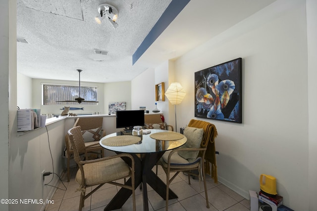 dining space with a textured ceiling and light tile patterned floors