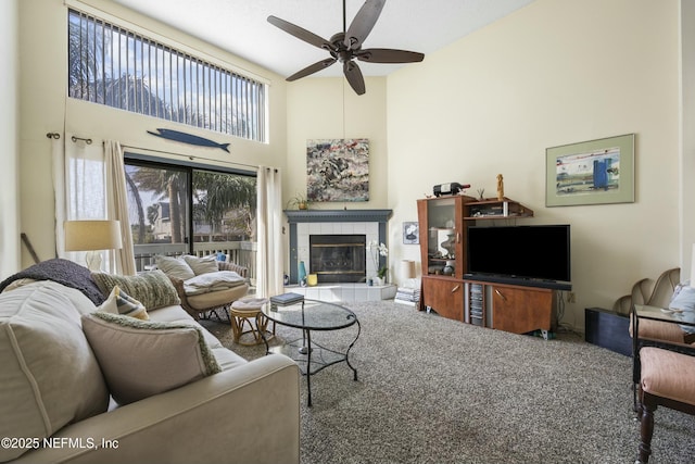 carpeted living room with a tile fireplace, a towering ceiling, and ceiling fan