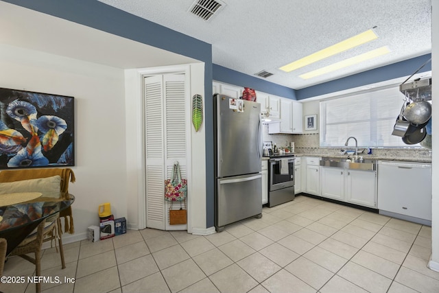 kitchen featuring white cabinetry, sink, light tile patterned flooring, and appliances with stainless steel finishes