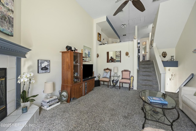 carpeted living room with ceiling fan and a tiled fireplace