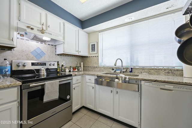 kitchen featuring dishwasher, sink, white cabinets, light tile patterned floors, and electric stove