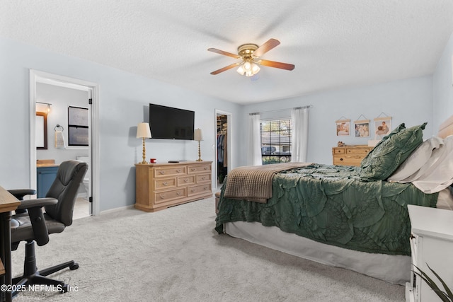 bedroom featuring a spacious closet, a textured ceiling, ensuite bath, a closet, and ceiling fan