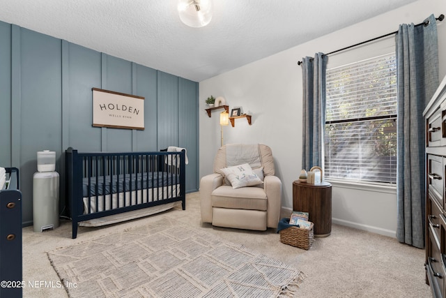 carpeted bedroom featuring a textured ceiling and a nursery area