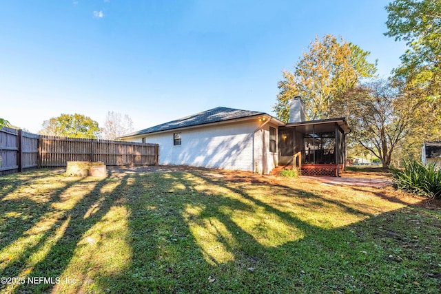 rear view of house featuring a sunroom and a yard