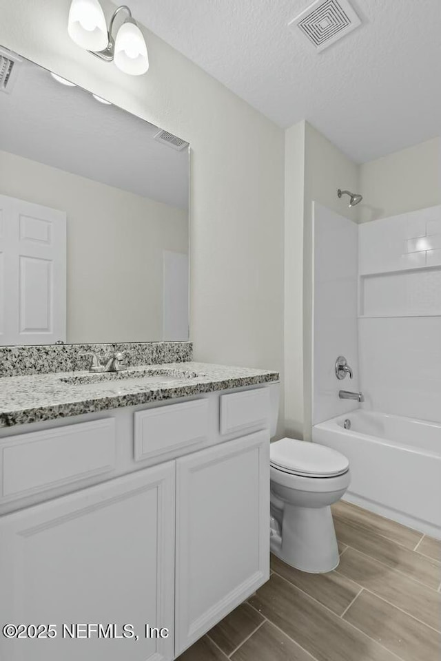 full bathroom with vanity, toilet, a textured ceiling, and shower / bathing tub combination