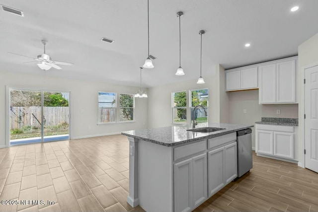 kitchen featuring dishwasher, sink, white cabinetry, light stone counters, and a kitchen island with sink