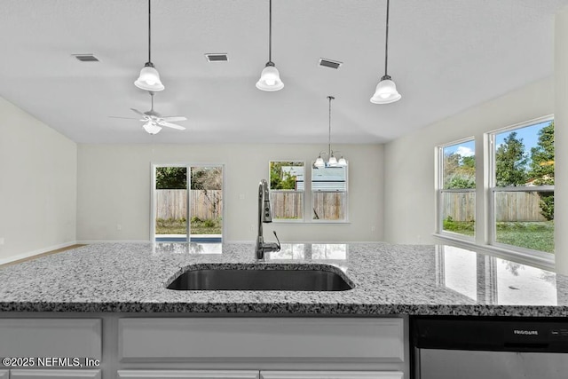 kitchen with sink, decorative light fixtures, light stone countertops, and stainless steel dishwasher