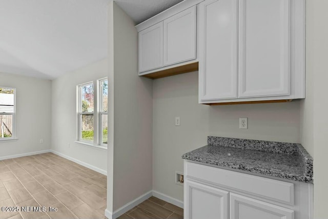 kitchen with white cabinetry, a wealth of natural light, and stone counters