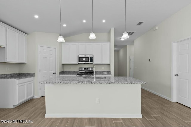 kitchen with white cabinetry, hanging light fixtures, a kitchen island with sink, and appliances with stainless steel finishes