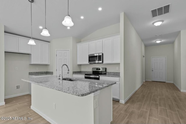 kitchen with light stone counters, a center island with sink, white cabinets, and stainless steel appliances