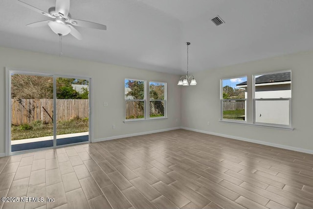 spare room featuring ceiling fan with notable chandelier