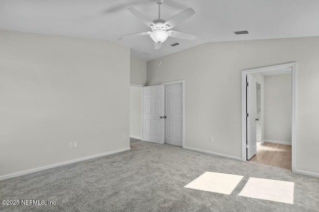 unfurnished bedroom featuring ceiling fan, light colored carpet, and lofted ceiling