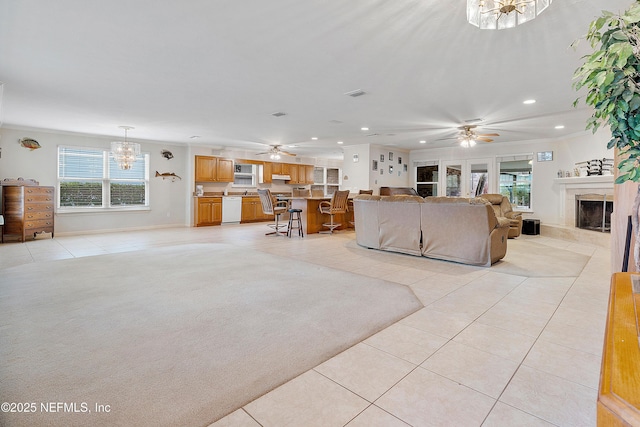 living room featuring light carpet, ceiling fan with notable chandelier, and a premium fireplace