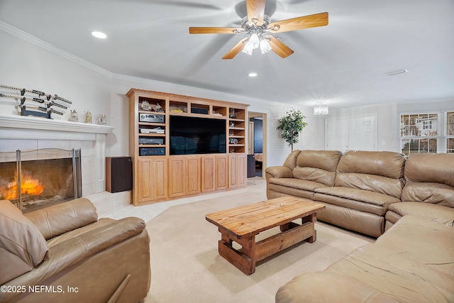 living room with crown molding, a tile fireplace, and ceiling fan