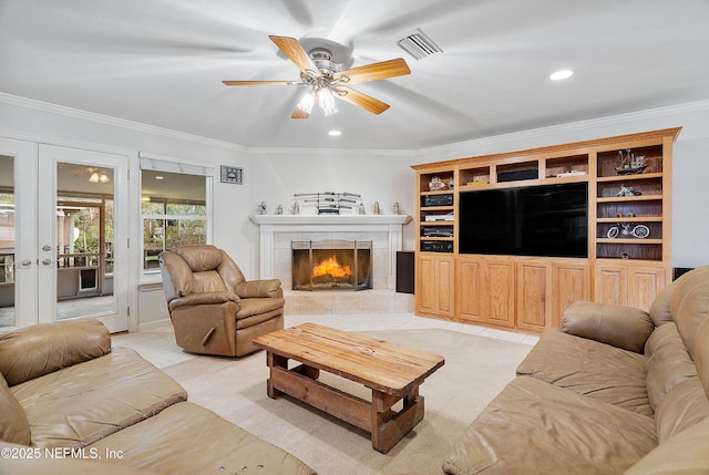 tiled living room with a tiled fireplace, ornamental molding, french doors, and ceiling fan