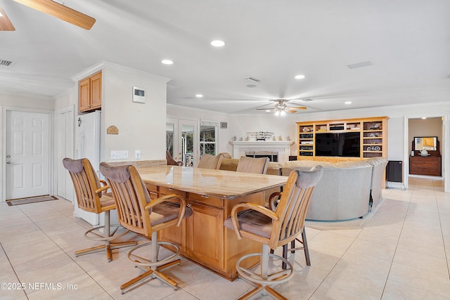 tiled dining space featuring crown molding and ceiling fan