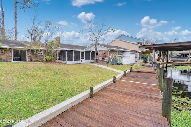 back of property featuring a yard, a sunroom, central air condition unit, and a water view