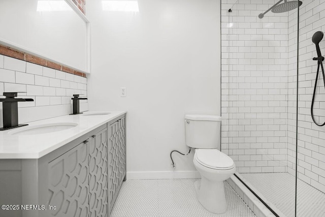 bathroom with tile patterned flooring, vanity, tiled shower, and toilet