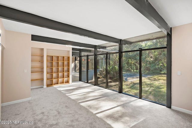 spare room with floor to ceiling windows, beam ceiling, and carpet floors