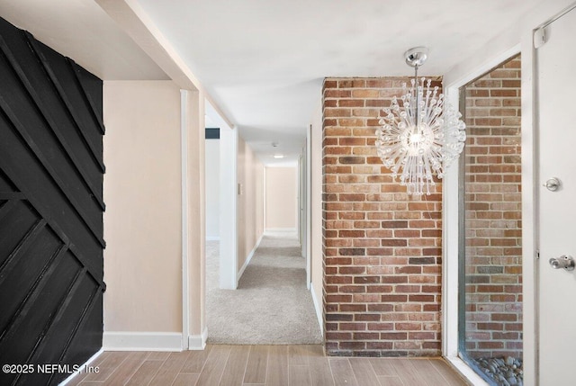 corridor with a notable chandelier and light wood-type flooring