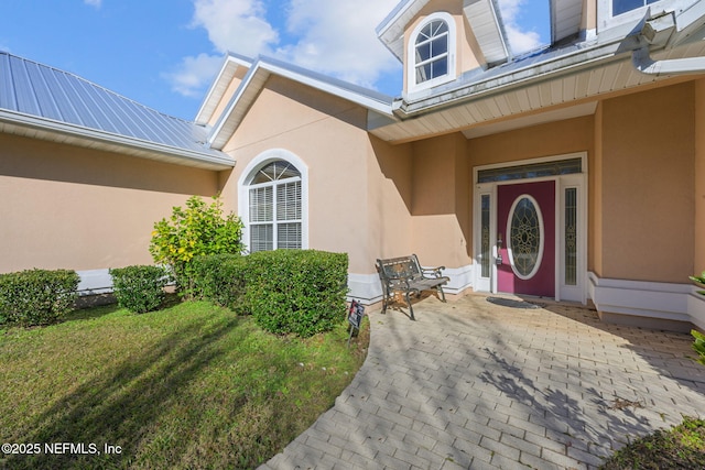 property entrance featuring a patio and a lawn