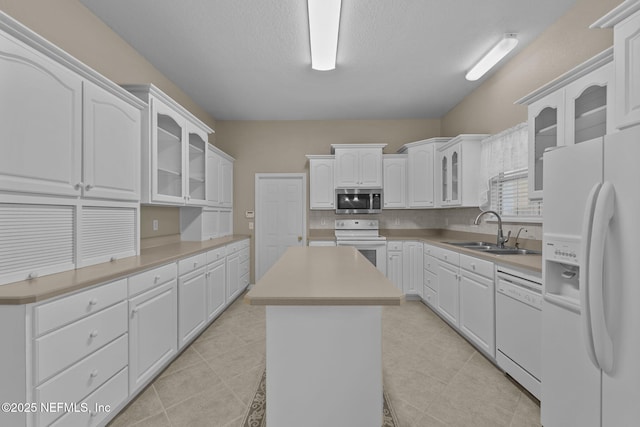 kitchen featuring sink, white appliances, white cabinetry, a textured ceiling, and a kitchen island