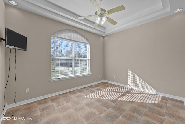 empty room featuring a raised ceiling and ceiling fan