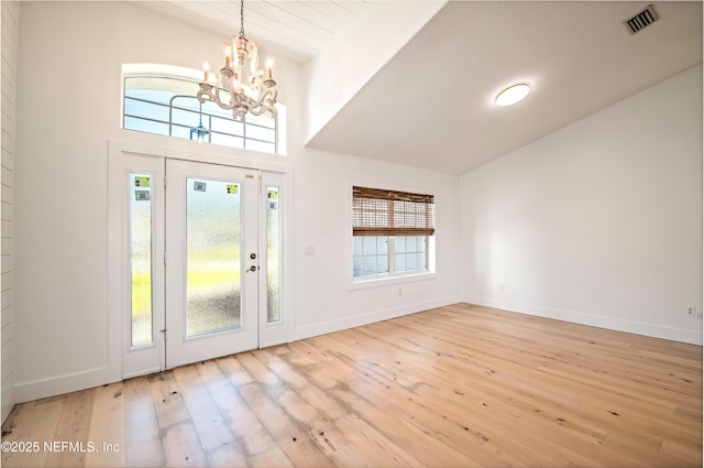 foyer with lofted ceiling, a healthy amount of sunlight, a chandelier, and light wood-type flooring