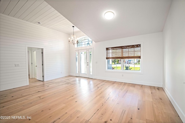 interior space with light hardwood / wood-style flooring, a notable chandelier, and wooden walls