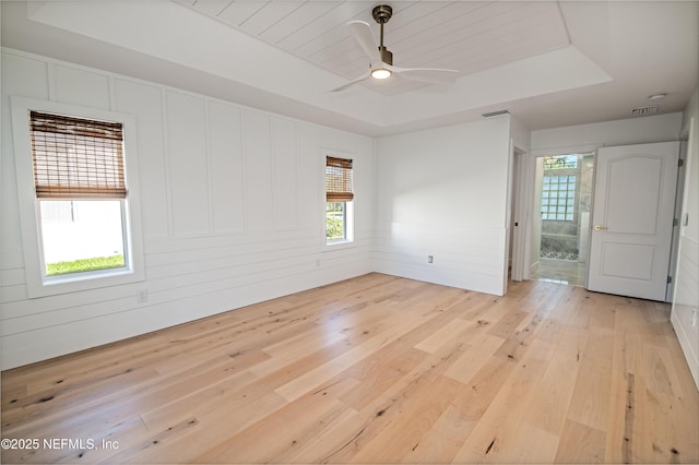 unfurnished room featuring wood ceiling, ceiling fan, a raised ceiling, and light wood-type flooring