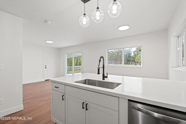 kitchen with hardwood / wood-style floors, dishwasher, white cabinetry, sink, and hanging light fixtures