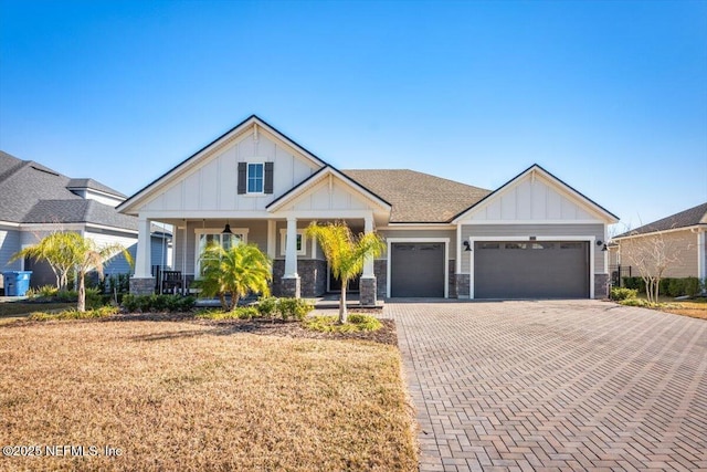 craftsman-style house with a garage, covered porch, and a front yard