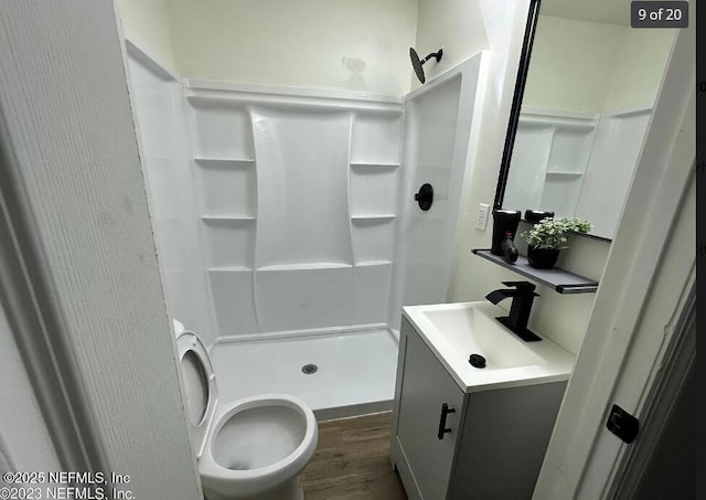 bathroom featuring wood-type flooring, toilet, walk in shower, and vanity