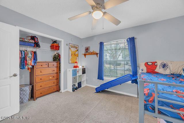 carpeted bedroom featuring ceiling fan and a closet