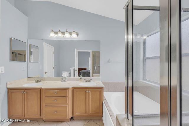 bathroom with tile patterned flooring, vanity, lofted ceiling, and shower with separate bathtub