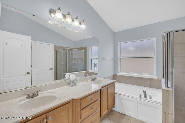 bathroom featuring vanity, vaulted ceiling, tile patterned floors, and shower with separate bathtub