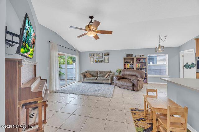 living room with lofted ceiling, light tile patterned floors, and ceiling fan