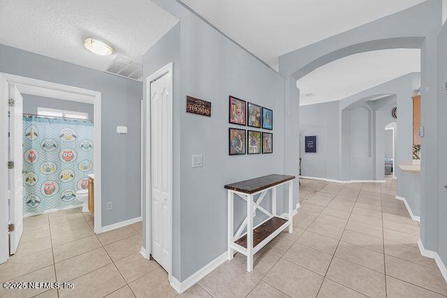 hall featuring light tile patterned flooring and a textured ceiling