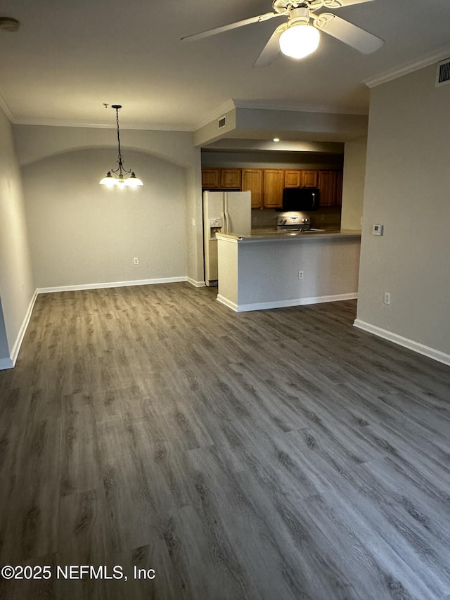 unfurnished living room with ceiling fan with notable chandelier, dark hardwood / wood-style floors, and ornamental molding