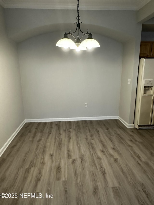 unfurnished dining area featuring wood-type flooring, crown molding, and an inviting chandelier