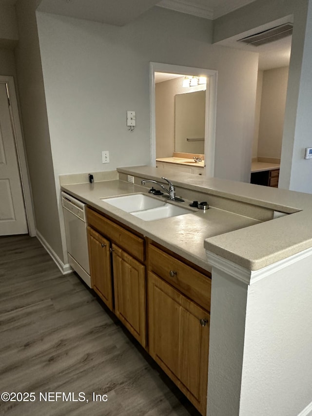 kitchen featuring hardwood / wood-style floors, dishwasher, sink, ornamental molding, and kitchen peninsula