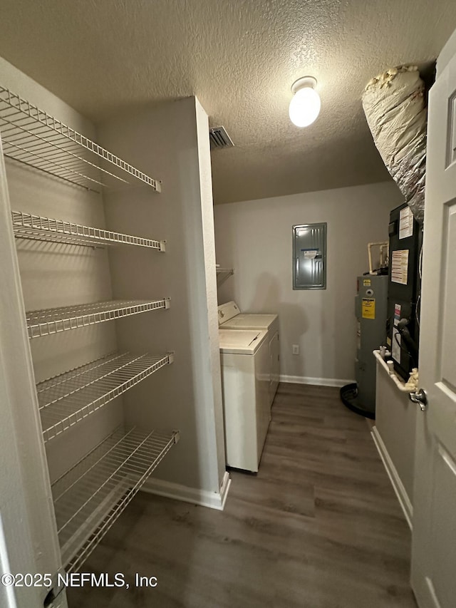 laundry area featuring a textured ceiling, dark wood-type flooring, separate washer and dryer, electric panel, and water heater