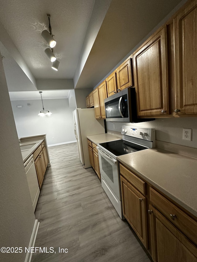 kitchen with white appliances, light hardwood / wood-style floors, a textured ceiling, sink, and pendant lighting