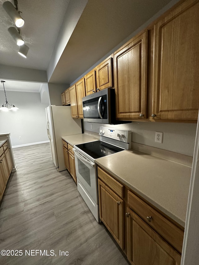 kitchen featuring pendant lighting, white appliances, and light wood-type flooring