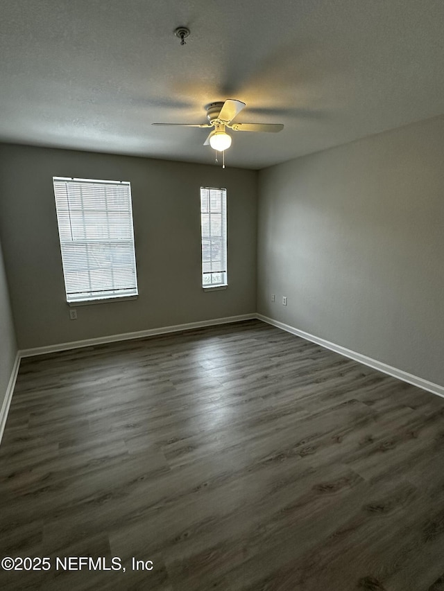 empty room featuring ceiling fan, dark wood-type flooring, and a textured ceiling