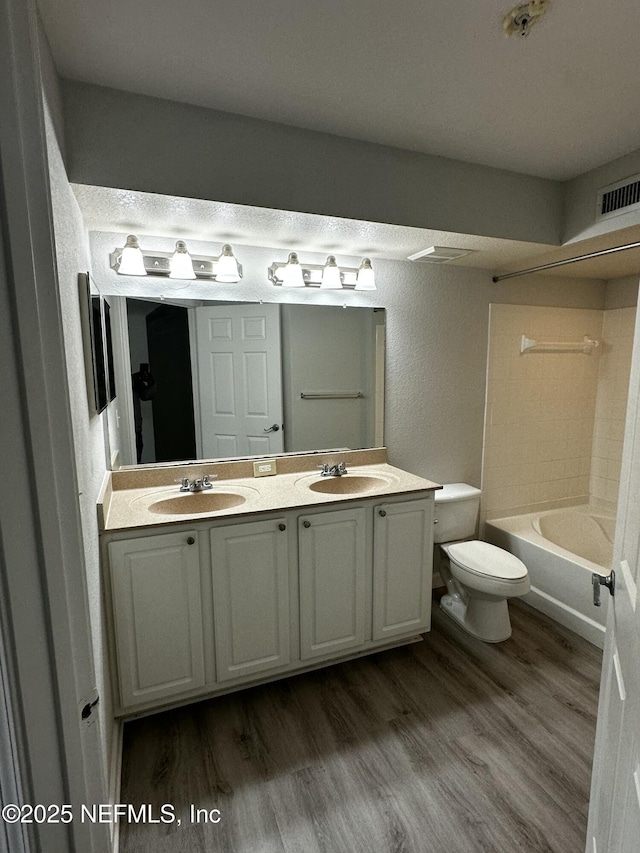 full bathroom with vanity, toilet, shower / bathtub combination, and hardwood / wood-style floors