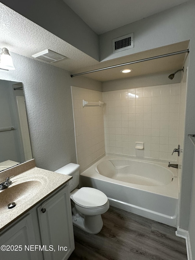 full bathroom featuring wood-type flooring,  shower combination, toilet, a textured ceiling, and vanity