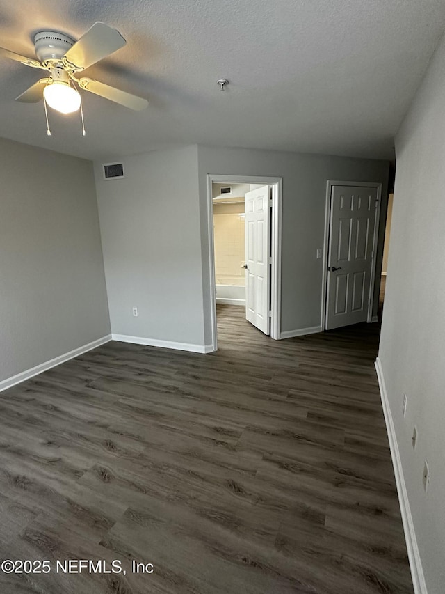 unfurnished room featuring ceiling fan, dark wood-type flooring, and a textured ceiling