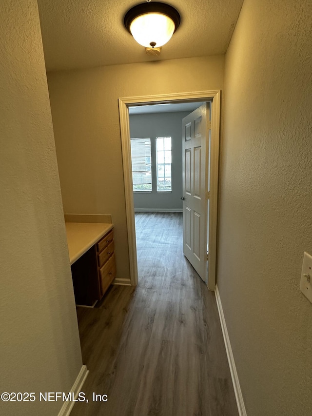 corridor with hardwood / wood-style flooring and a textured ceiling