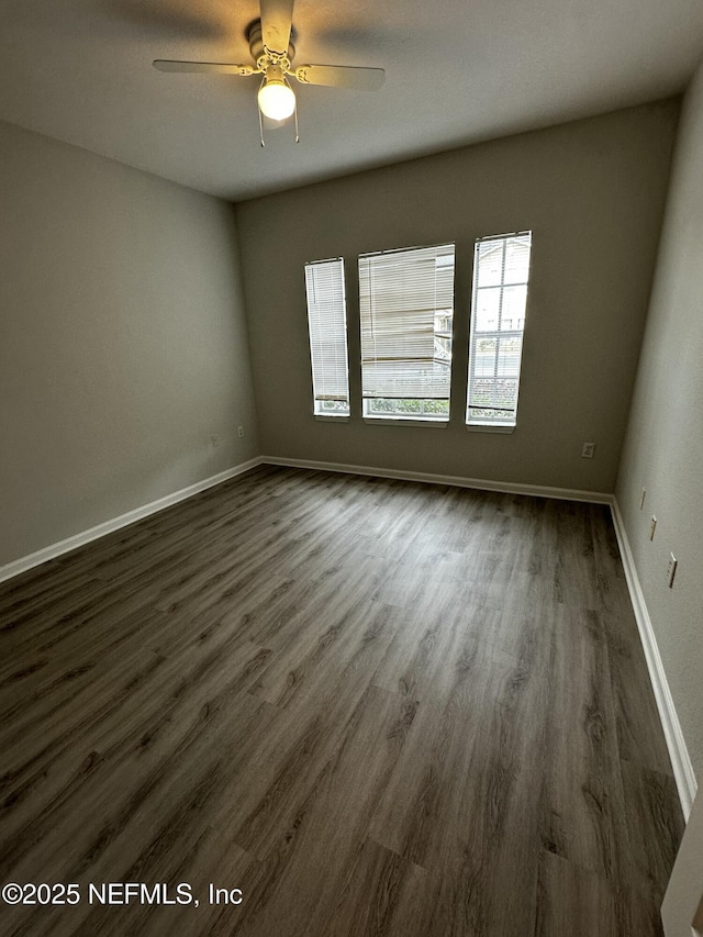 unfurnished room with ceiling fan and dark wood-type flooring